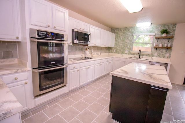 kitchen with white cabinetry, sink, light stone countertops, light tile patterned floors, and appliances with stainless steel finishes