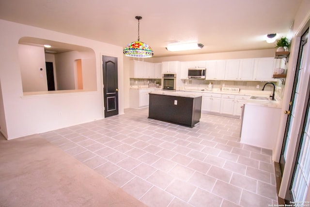 kitchen with a center island, white cabinets, sink, hanging light fixtures, and appliances with stainless steel finishes