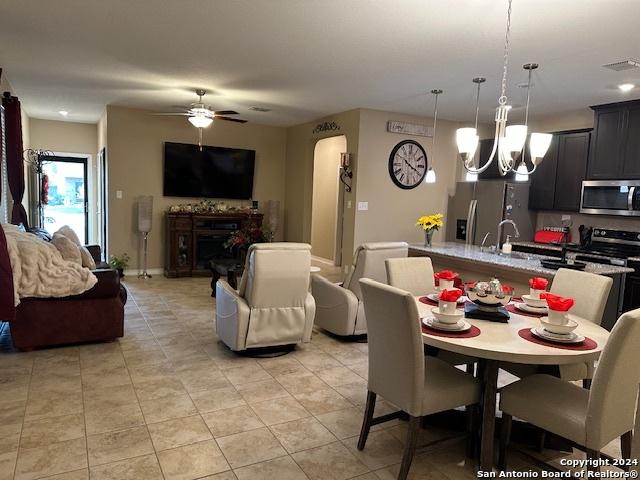 tiled dining space with ceiling fan with notable chandelier