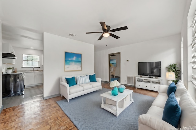 living room featuring light parquet floors, ceiling fan, and sink