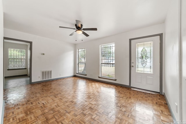 foyer entrance with ceiling fan, a healthy amount of sunlight, and parquet floors