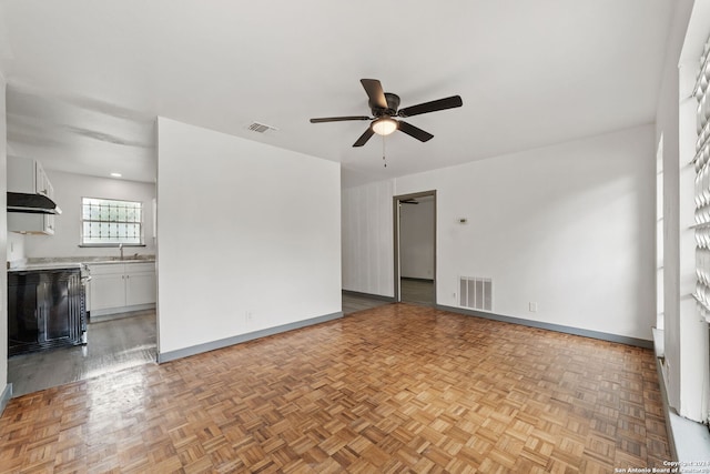 unfurnished room with ceiling fan, sink, and light parquet floors