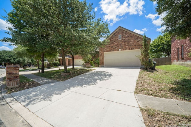 view of front facade featuring driveway, a garage, brick siding, fence, and a front yard