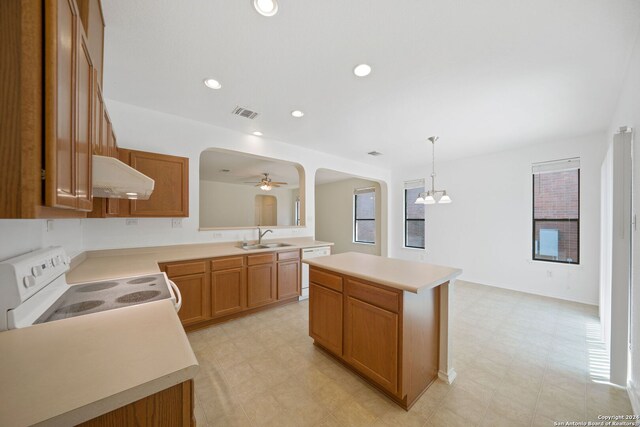 kitchen featuring white appliances, wall chimney range hood, a kitchen island, pendant lighting, and sink