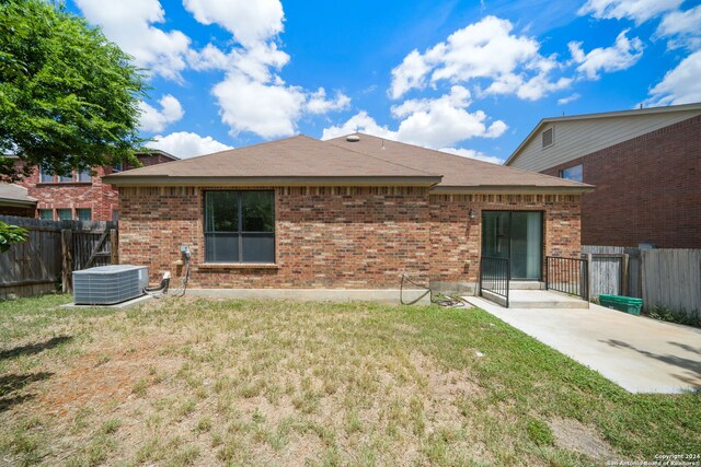 back of house with central AC unit and a yard