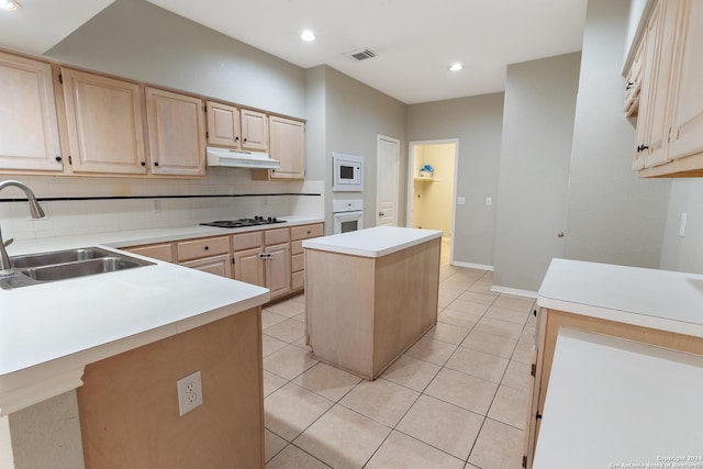 kitchen with light brown cabinetry, sink, white appliances, and a center island