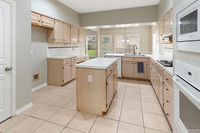 kitchen with sink, light brown cabinets, a kitchen island, pendant lighting, and white appliances