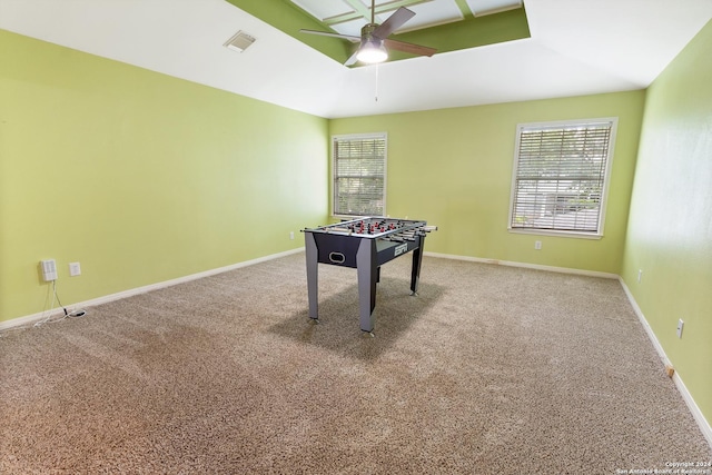 playroom with carpet flooring, ceiling fan, and a tray ceiling