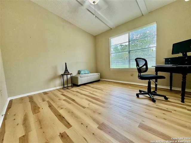 office featuring vaulted ceiling, light hardwood / wood-style floors, and a textured ceiling