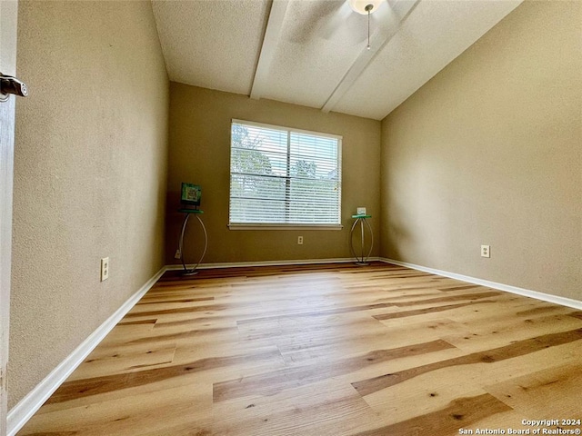 empty room with light hardwood / wood-style flooring and vaulted ceiling