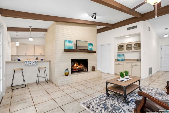 living room with vaulted ceiling with beams, a fireplace, and light tile patterned floors