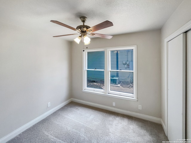 unfurnished bedroom with a textured ceiling, ceiling fan, carpet flooring, and a closet