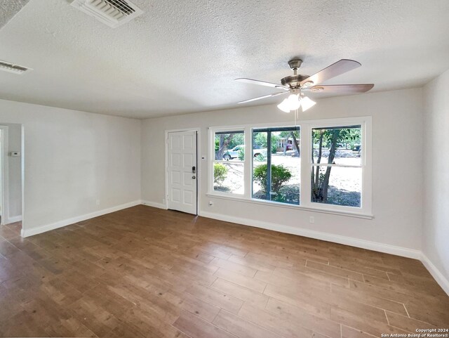 spare room with dark hardwood / wood-style floors, a textured ceiling, and ceiling fan