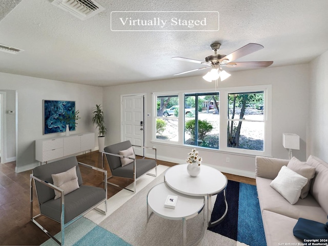 living room featuring ceiling fan, hardwood / wood-style floors, and a textured ceiling