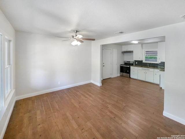 kitchen with sink, white cabinets, stainless steel range with electric stovetop, ceiling fan, and light wood-type flooring