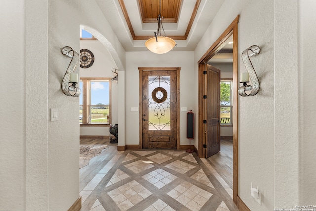 foyer with light wood-type flooring and a raised ceiling