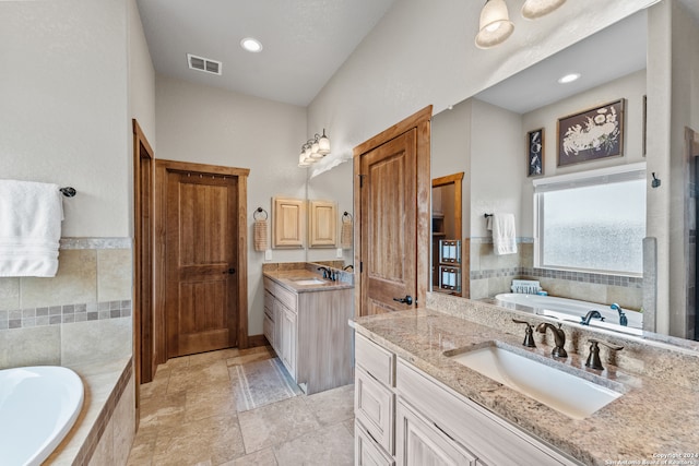 bathroom featuring tiled tub, tile patterned floors, and double sink vanity