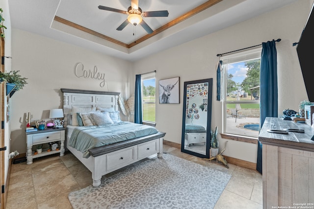 tiled bedroom featuring multiple windows, ceiling fan, and a raised ceiling