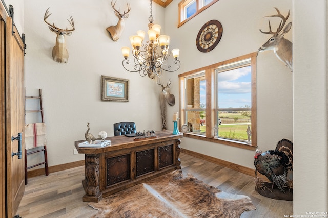 office space featuring hardwood / wood-style floors, a barn door, and an inviting chandelier