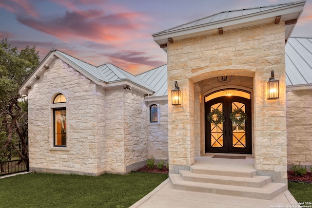 exterior entry at dusk featuring a yard and french doors