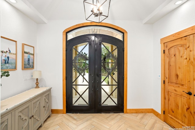 entrance foyer with light parquet floors, a notable chandelier, and french doors