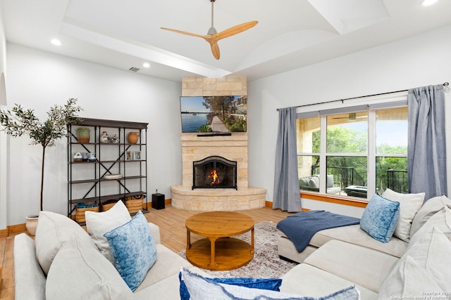 living room featuring a tray ceiling, ceiling fan, a fireplace, and hardwood / wood-style flooring