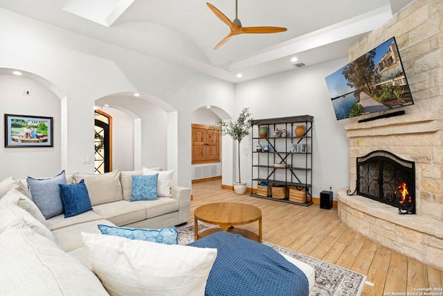 living room with a stone fireplace, hardwood / wood-style floors, and ceiling fan