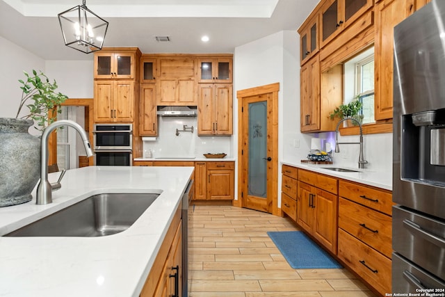 kitchen featuring stainless steel appliances, decorative light fixtures, light hardwood / wood-style flooring, and sink