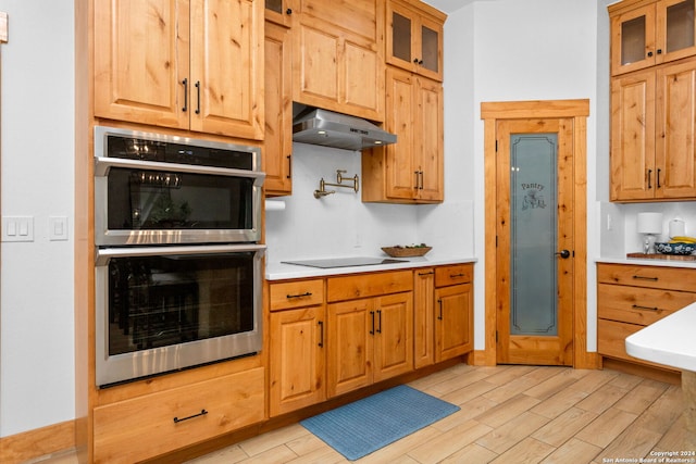 kitchen featuring black electric stovetop, light hardwood / wood-style flooring, stainless steel double oven, and wall chimney range hood