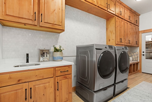 clothes washing area featuring cabinets, washing machine and dryer, and sink