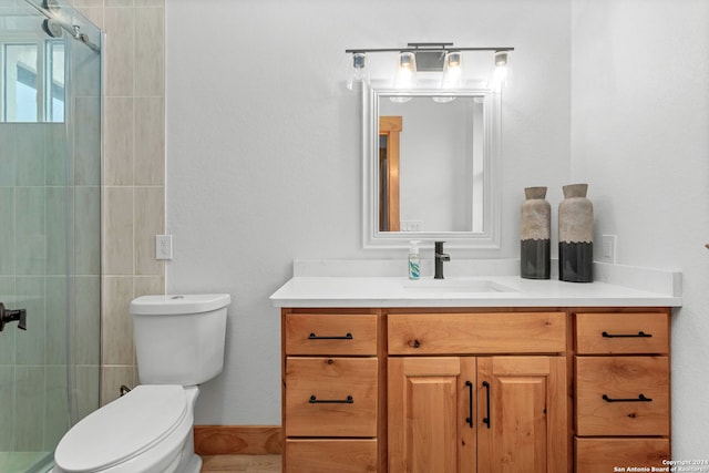 bathroom featuring a shower with shower door, toilet, and vanity