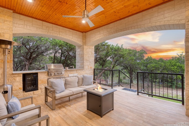 deck at dusk with an outdoor living space with a fire pit, grilling area, ceiling fan, and area for grilling