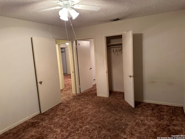 unfurnished bedroom with dark colored carpet, a textured ceiling, and ceiling fan