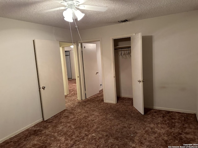 unfurnished bedroom with ceiling fan, dark carpet, and a textured ceiling