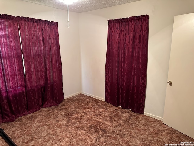 carpeted empty room with a textured ceiling