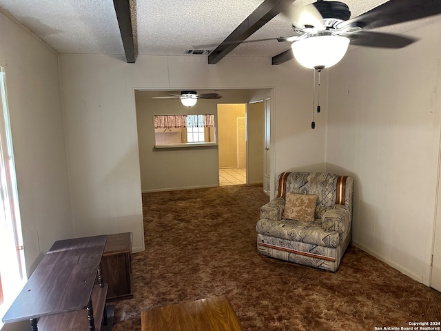 living area with a textured ceiling, carpet flooring, beam ceiling, and ceiling fan