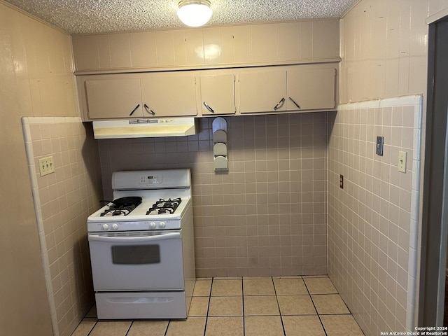 kitchen with tile walls, light tile patterned floors, a textured ceiling, and white gas stove