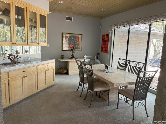 dining room featuring wooden ceiling, light colored carpet, and a healthy amount of sunlight