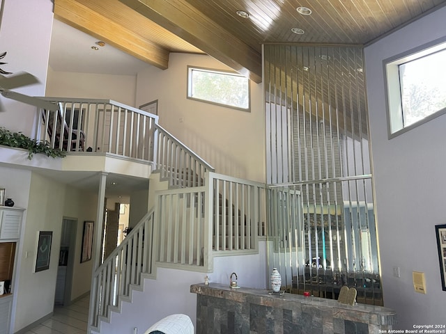 stairs featuring wood ceiling, a high ceiling, and beamed ceiling