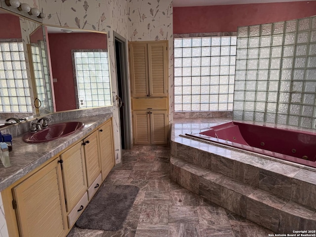 full bath with a whirlpool tub, wallpapered walls, and vanity