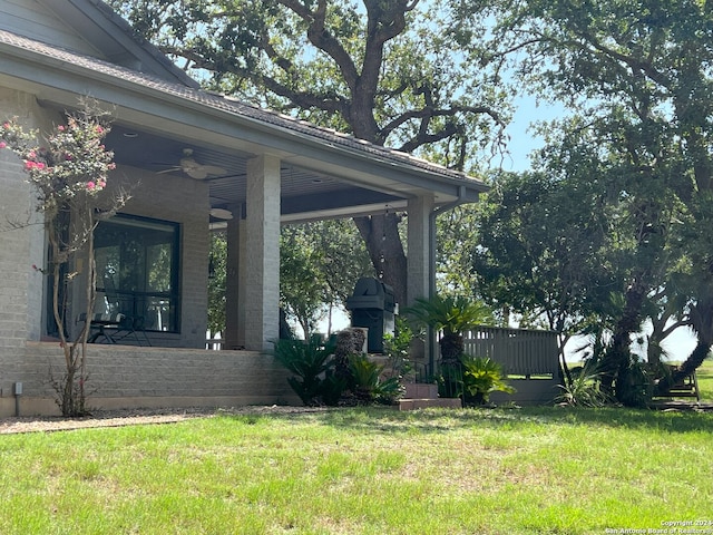 view of yard featuring covered porch and a ceiling fan