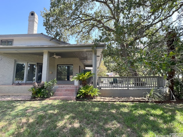 exterior space featuring a chimney, a ceiling fan, and a yard