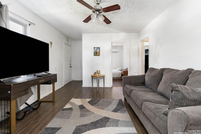 living room with dark hardwood / wood-style flooring, a textured ceiling, and ceiling fan