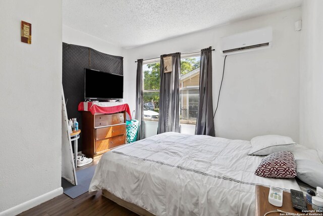 bedroom with dark wood-type flooring, a wall mounted AC, and a textured ceiling