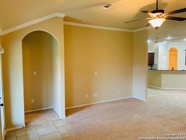 tiled empty room featuring ornamental molding and ceiling fan