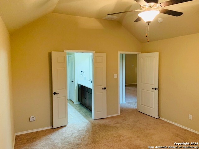 unfurnished bedroom featuring lofted ceiling, light colored carpet, and ceiling fan