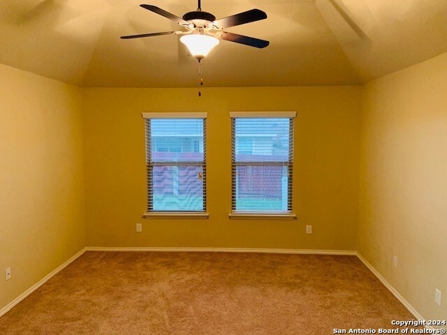 empty room featuring lofted ceiling, ceiling fan, and carpet