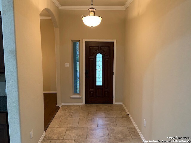 foyer with light tile patterned flooring and ornamental molding