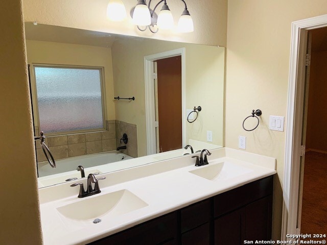 bathroom featuring a washtub and double sink vanity