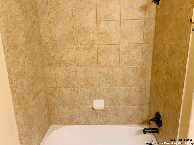 interior details featuring tiled shower / bath combo